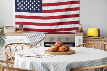 Hanging USA flag and tasty buns on table in kitchen
