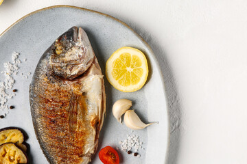 Plate with tasty grilled dorado fish on white background