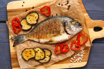 Board with tasty grilled dorado fish on blue wooden background