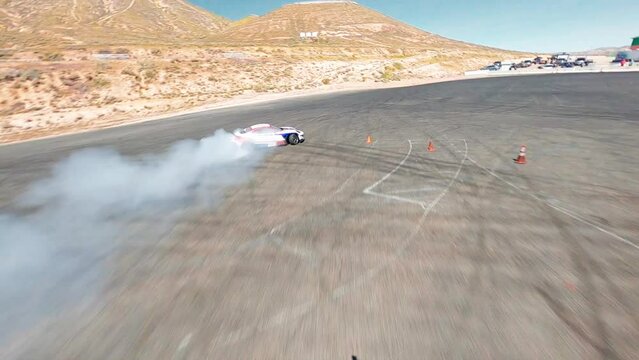 FPV, CALIFORNIA, USA - April 8, 2023: Aerial top view professional driver drifting car on asphalt road track, Automobile  drift on abstract asphalt road tire skid mark with lot of smoke of car