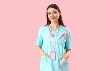 Female medical intern with stethoscope on pink background