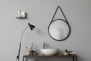 Table with sink bowl, bath accessories and mirror in bathroom