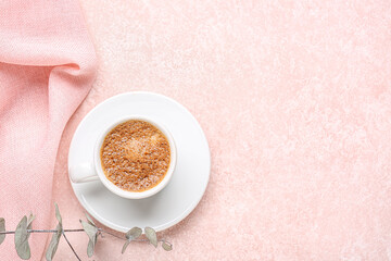 Cup of hot espresso and eucalyptus on pink background