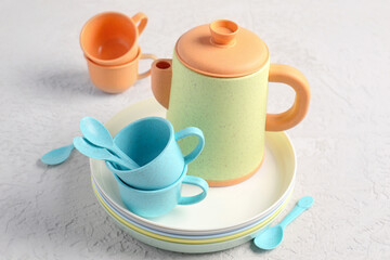 Plates with cups, teapot and spoons for baby on grunge white table