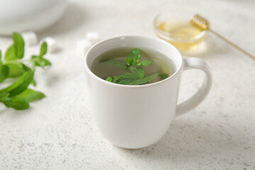 Cup of fresh mint tea with honey on grunge light background