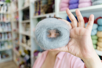 Woman hand holding the ball of grey colored mohair yarn