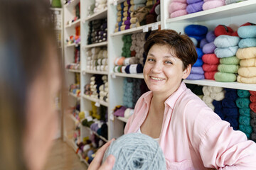 Young woman smiling while choosing the yarn for her new knitting sweater