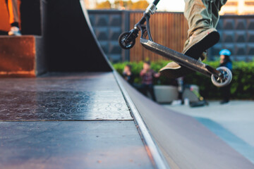 Skate park with kids on a kick scooter doing tricks and stunts, boys in a skate park riding bmx...