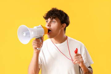 Male lifeguard with whistle shouting into megaphone on yellow background