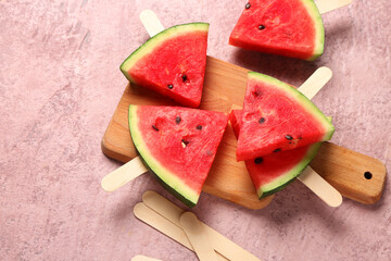 Wooden board with sweet watermelon sticks on pink background
