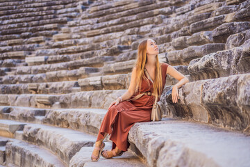 Fototapeta premium Woman tourist explores Aspendos Ancient City. Aspendos acropolis city ruins, cisterns, aqueducts and old temple. Aspendos Antalya Turkey. turkiye