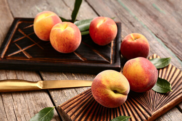 Boards with sweet peaches and leaves on wooden background
