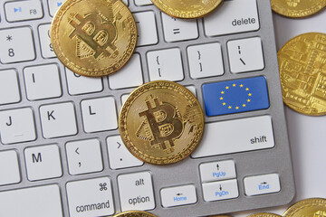 national flag of european union on the keyboard with bitcoin coins on a grey background.