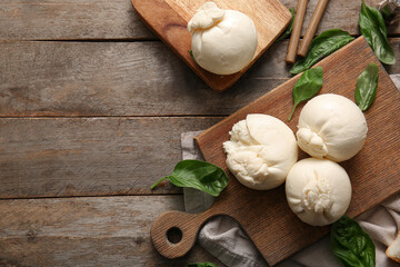 Boards of tasty Burrata cheese with basil on wooden background