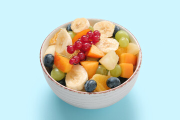 Bowl with fresh fruit salad on blue background