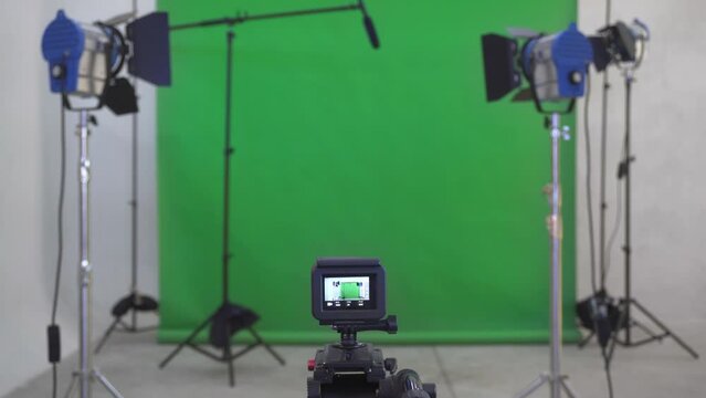 Preparing the set: Professional recording equipment ready in the studio. Creation of multimedia content in action. Sports camera, lights, microphone and green screen.