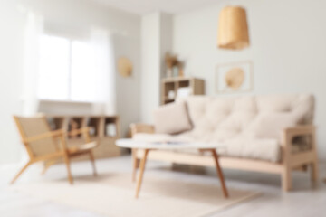Blurred view of living room interior with white sofa, armchair and coffee table