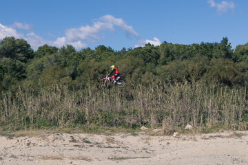 Photo of a motocross while it is flying in the middle of nature 