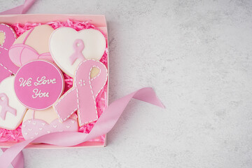 Box with pink cookies and ribbon on white grunge background. Breast cancer awareness concept