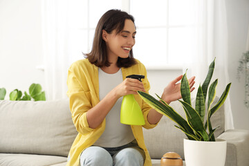 Young woman watering plant at home
