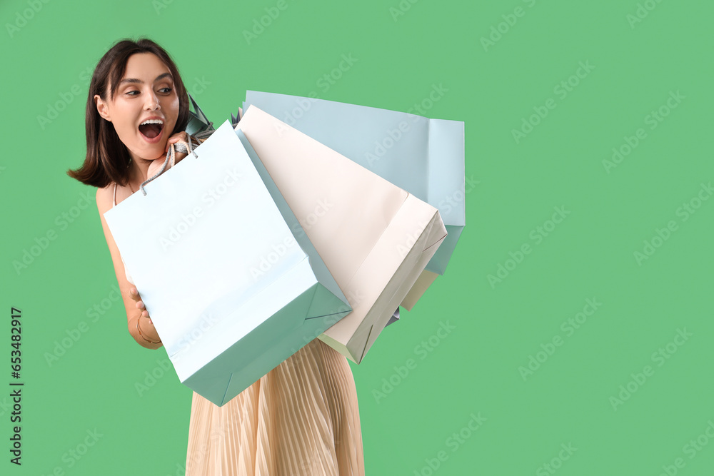 Wall mural Young woman with shopping bags on green background. Black Friday sale