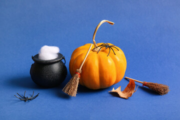 Halloween composition with pumpkin, broom and cauldron on blue background