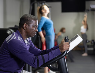 Fototapeta premium African-american man training on exercise bike in gym