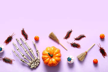 Halloween composition with candy bugs, pumpkins, skeleton hand and brooms on lilac background