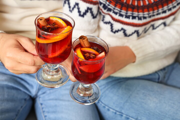 Young couple with glasses of mulled wine at home on Christmas eve, closeup