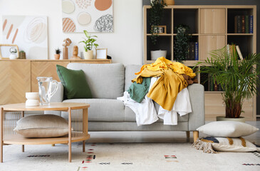 Interior of living room with dirty clothes on sofa