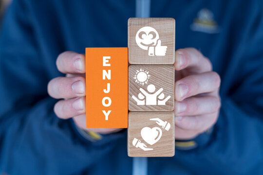 Man holding colorful blocks sees word: ENJOY. Motivation, inspiration life style concept. Enjoying every moment. Enjoyment. - Powered by Adobe
