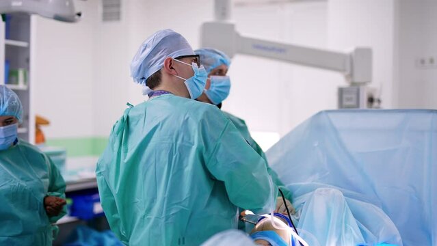 Male surgeon performing laparoscopic operation. Professional uses modern surgical appliances. Doctors look at the monitor controlling the procedure.