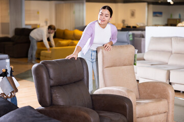 Young woman is examining a new armchair in a furniture store