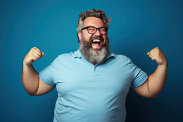 Excited fat man celebrating success. Happy plus size bearded man on blue background