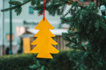 Christmas tree yellow figurine on a fir branch .Christmas street decorations in European cities.Wooden Outdoor Decor for Trees.Christmas time in Europe.Festive cozy mood. 