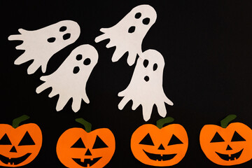 paper ghosts and pumpkins on a black background