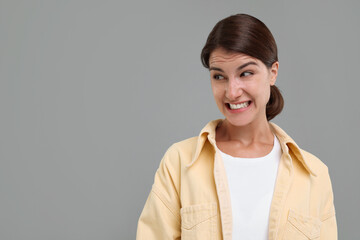 Obraz premium Portrait of embarrassed young woman on grey background, space for text