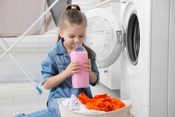 Little girl smelling fabric softener in bathroom