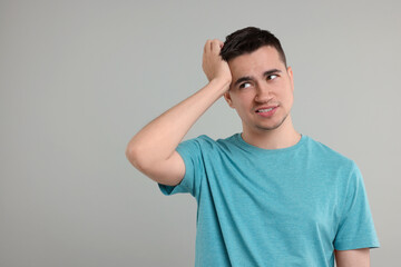 Embarrassed man on grey background. Space for text