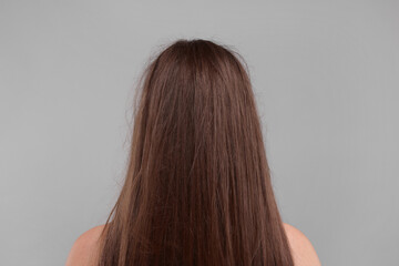Woman with damaged hair on light grey background, back view