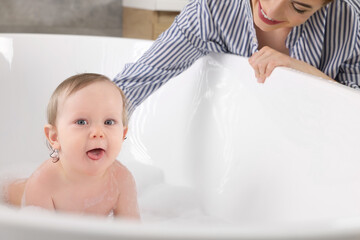 Mother washing her little baby in tub at home, closeup