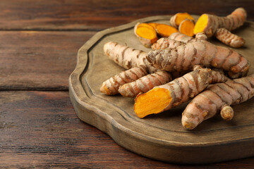 Many fresh turmeric roots on wooden table, closeup. Space for text