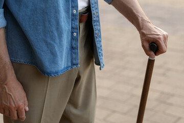 Senior man with walking cane outdoors, closeup
