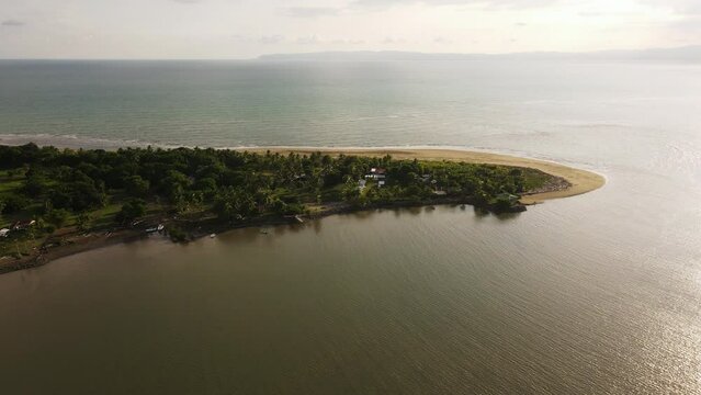 Aerial view of a peninsula in Costa Rica, showcasing a strong contrast between the golden sunlight and the lush greenery. This scenic landscape is located in Zancudo, Costa Rica.