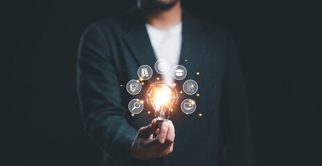 Businessman holding glowing lightbulb with learning icons for study knowledge to creative thinking idea and problem solving solution concept. - obrazy, fototapety, plakaty