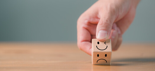 Mental health and emotional state concept, Smile face in bright side and sad face in dark side on wooden block cube for positive mindset selection.