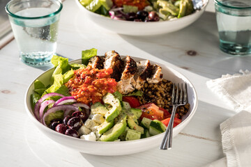 A close up of a healthy Mediterranean bowl topped with roasted red pepper sauce.