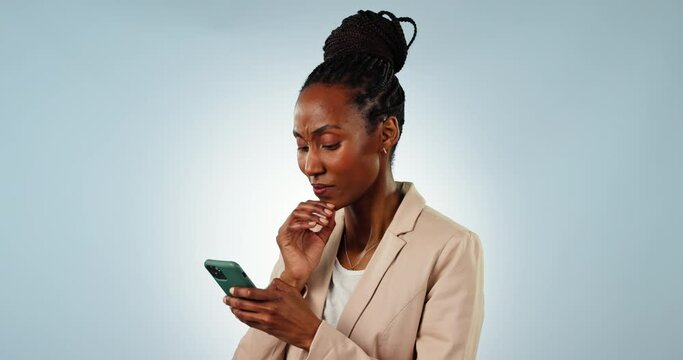 Thinking, phone and black woman in a studio networking on social media, mobile app or the internet. Brainstorming, technology and young African female model scroll on a cellphone by gray background.