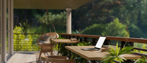 A laptop on a table on a home or apartment balcony with a beautiful green nature view.