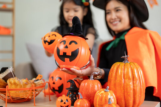 Close-up image of a mom and little daughter enjoying decorating their house with Halloween stuff.